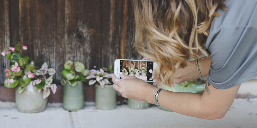 Woman taking a photo of potted plants with a smart phone | Retail Shift Podcast Episode 1: Shifting the Customer Service Role from Seller to Entertainer | Hosted by Chris Guillot of Merchant Method | Subscribe at merchant.tips/podcast