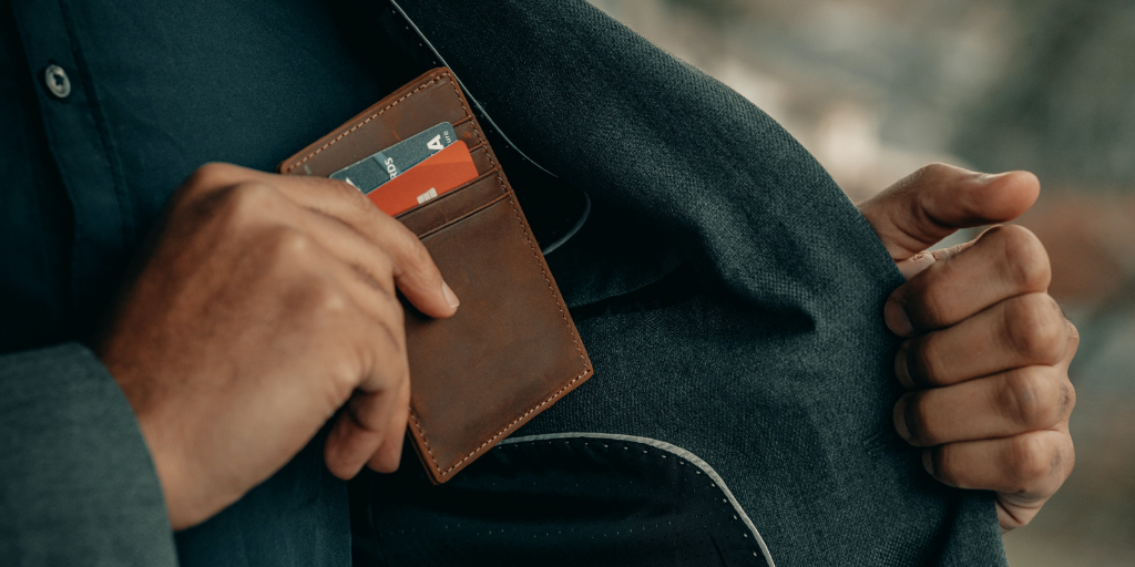 A man putting his wallet inside his front jacket pocket 